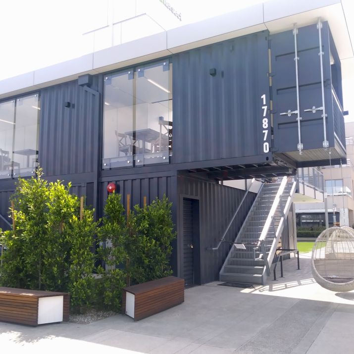 A contemporary office building featuring a shipping container attached to its side, showcasing innovative architectural design.