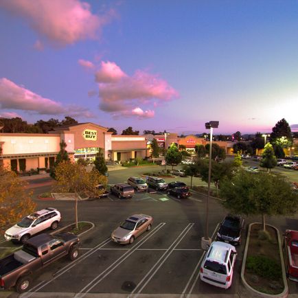 A parking lot filled with parked cars, illuminated by the soft glow of dusk.