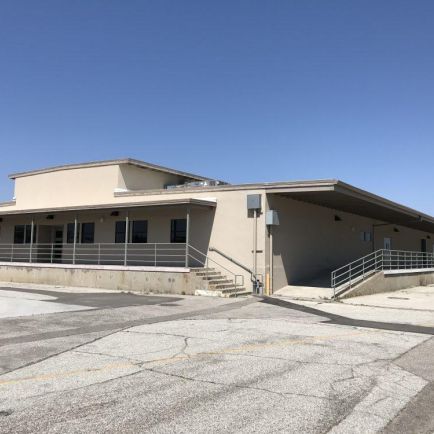 An empty building with a spacious parking lot, devoid of vehicles or activity, highlighting its desolate appearance.