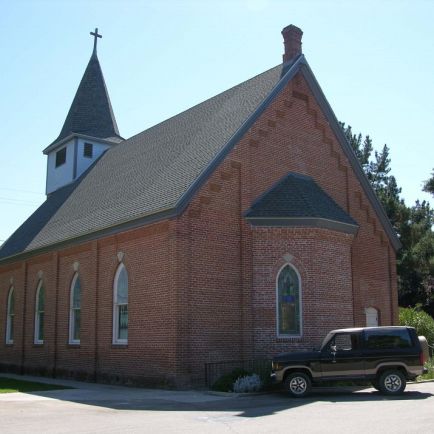 A church building with a car parked in front, showcasing a serene and peaceful environment. 