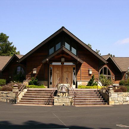 A large wooden church stands prominently, accompanied by an expansive driveway leading to its entrance.
