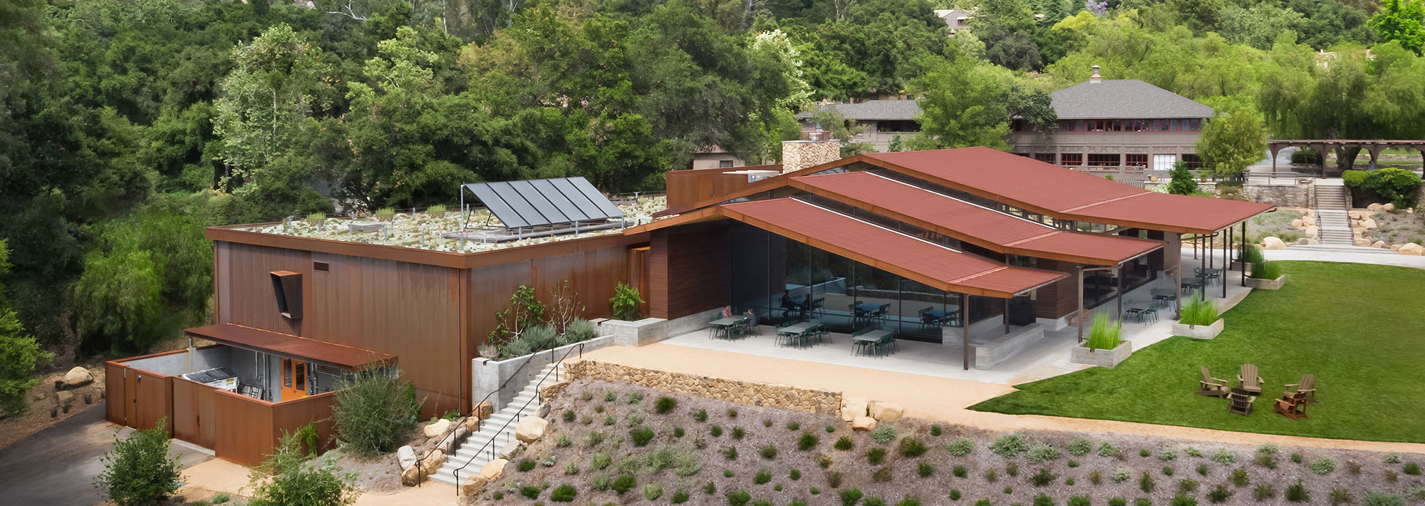 A modern pavilion showcasing innovative architecture amidst lush greenery and vibrant animal exhibits.
