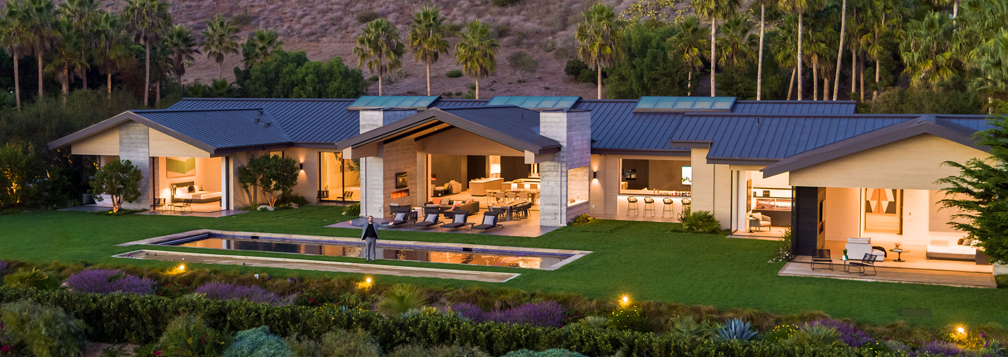 A contemporary home featuring a swimming pool surrounded by lush landscaping, showcasing modern architectural design.