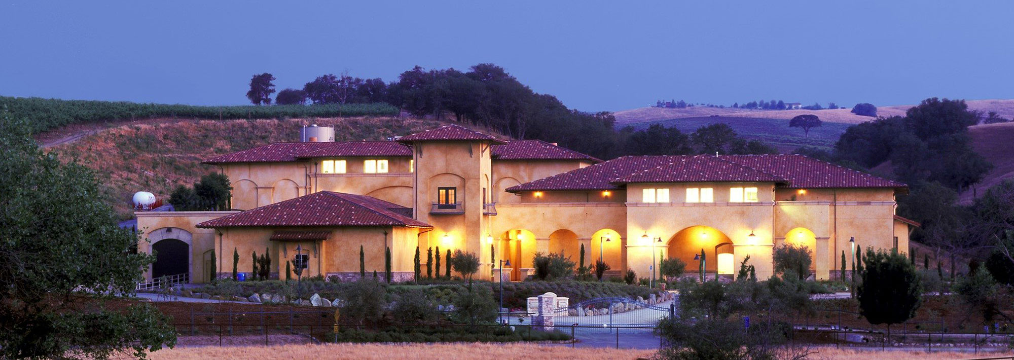 A grand mansion surrounded by a spacious lawn and a wide driveway, showcasing its impressive architecture and elegance.  